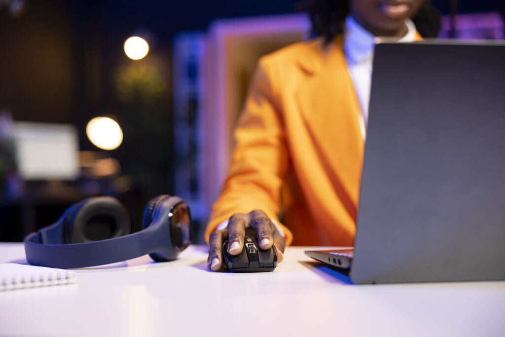A remote professional using a computer mouse and laptop, representing the difference between outsourcing, BPO, and offshoring.