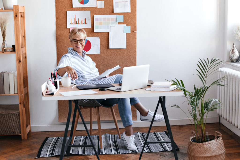 Business professional sitting at a desk holding documents while reviewing Employer of Record (EOR) expansion data on a laptop.